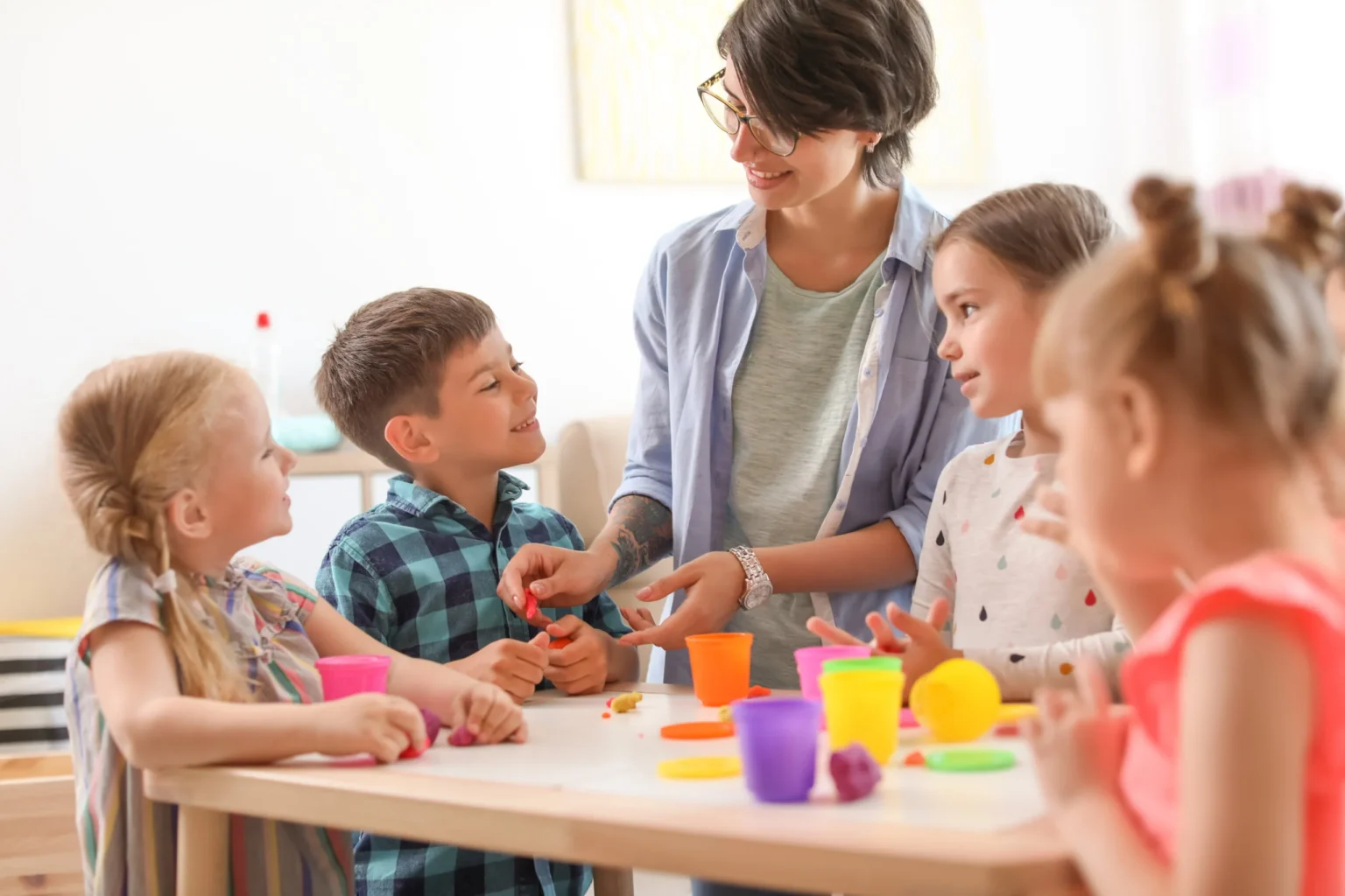 Stagiaire en crèche encadrant une activité manuelle avec de jeunes enfants